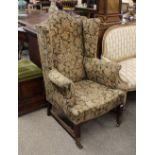 A 19th Century mahogany framed wing back armchair, raised on square tapering supports, united by