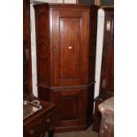 An Antique elm floor standing corner cupboard, enclosed by moulded panelled doors, the side panels
