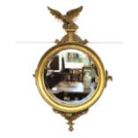 A Regency circular gilt framed and bevel edged wall mirror, with eagle surmount and acanthus