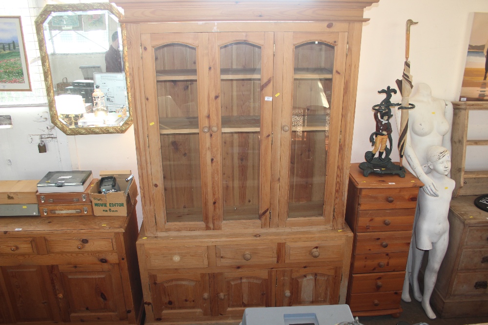 A pine bookcase raised on cupboard base fitted th