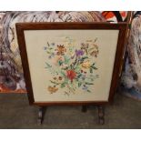 A 1930's oak folding fire screen/occasional table, with floral embroidered panel