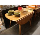 An Ercol drop leaf kitchen table, raised on square tapering supports