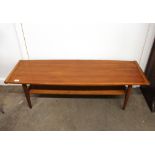 A teak long coffee table, with magazine under-tier, raised on square section tapering supports,