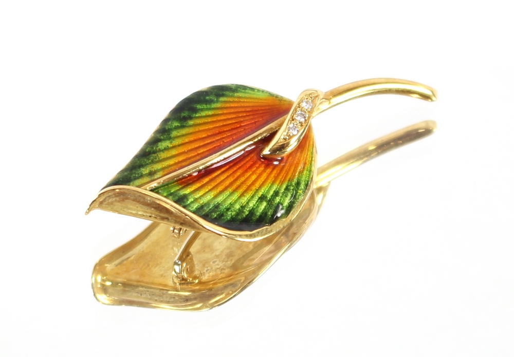 A yellow metal and enamel leaf shaped brooch, set