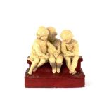 An Art Deco design glazed plaster figure group, depicting three young children sat on a wall, 31cm