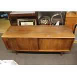 A teak long sideboard, enclosed by sliding doors, raised on rounded tapering supports, 152cm wide