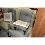 A green upholstered wing back arm chair and matchi