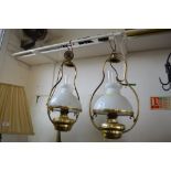 Two brass hanging oil lamps with milk glass shades