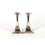 A pair of 18th Century French silver square based candlesticks, having detachable sconces 16cm high,