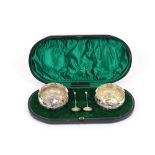 A pair of Victorian silver salts, having floral embossed decoration, shaped borders, raised on