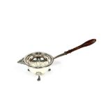 A modern silver tea strainer, having turned wooden handle and a bowl, raised on three pad feet