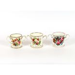 Three 19th Century Coalport style porcelain two handled mugs, decorated with flowers and