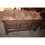 An Antique oak coffer, having triple panelled lid above carved frieze and panels, raised on square