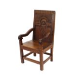 A heavy carved oak Wainscot type elbow chair, having foliate carved arched panel back, scroll arms