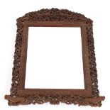 An ornately carved Indian frame, having later mirrored plate, 69cm x 52cm overall
