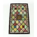An antique stained glass leaded panel, with coloured bosses and central foliate motif (some damage),