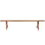 A pair of antique fruit wood long benches, raised on turned baluster supports, united by stretchers,