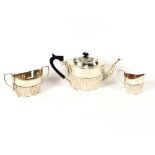 A late Victorian silver three piece tea set, having half fluted body decoration, the teapot with