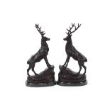 A pair of bronze stags, raised on rock work bases