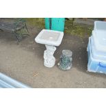 A concrete bird bath decorated with a squirrel tog