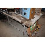 An antique rustic kitchen table on iron wheeled ba
