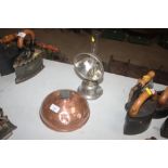 A copper hot water bottle and an oil lamp with a