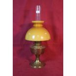A brass oil lamp with amber coloured opaque glass