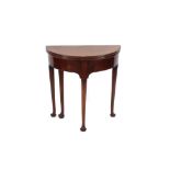 A Georgian mahogany demi-lune fold over tea table, raised on rounded tapering supports and pad feet,
