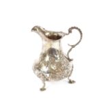 An early Victorian silver baluster cream jug, having foliate scroll decoration raised on three pad