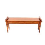 A Regency style mahogany window seat, having turned scroll ends raised on tapering turned supports