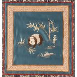A Chinese silk and needlework panel, depicting Panda amongst bamboo shoots, having stylised motif