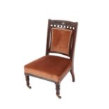 An Edwardian carved mahogany nursing chair, having pink dralon upholstered seat and back, raised