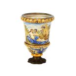 An Antique majolica urn, decorated with classical figures, raised on a later metalware base, 29cm
