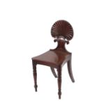 A pair of Regency mahogany hall chairs, having fan shaped backs, raised on ring turned tapering