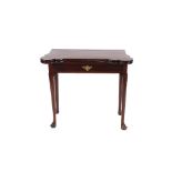 A Georgian mahogany card table, the shaped fold over baize lined top with sunken counter wells,