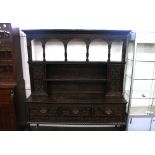 An antique carved oak dresser, in the Jacobean style having raised canopy back above cupboards and