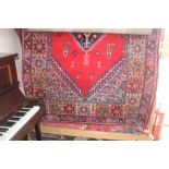 An approximate 8' x 5'5" red patterned wool rug