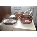 Two copper plated and brass handled saucepans; and