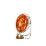 A white metal dress ring with amber coloured stone