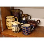 A collection of glazed earthenware jugs; and a bro
