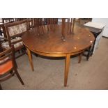 A circular topped extending dining table raised on