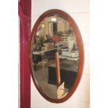 An oval inlaid mahogany bevelled edge wall mirror