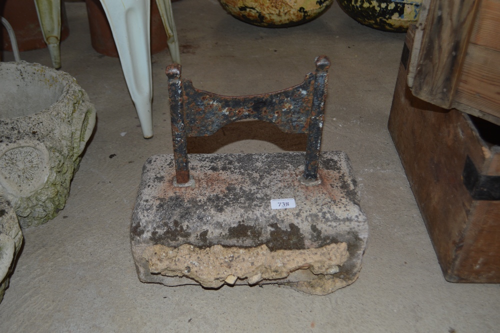 A cast iron boot scraper on concrete plinth