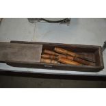 A wooden toolbox and contents of various chisels