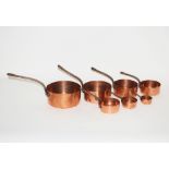 A set of seven graduated copper saucepans with iro