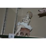 A Lladro figurine in the form of a young girl seat