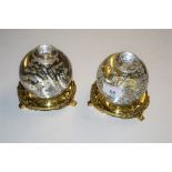 A pair of large bubble glass inkwells on gilt bras