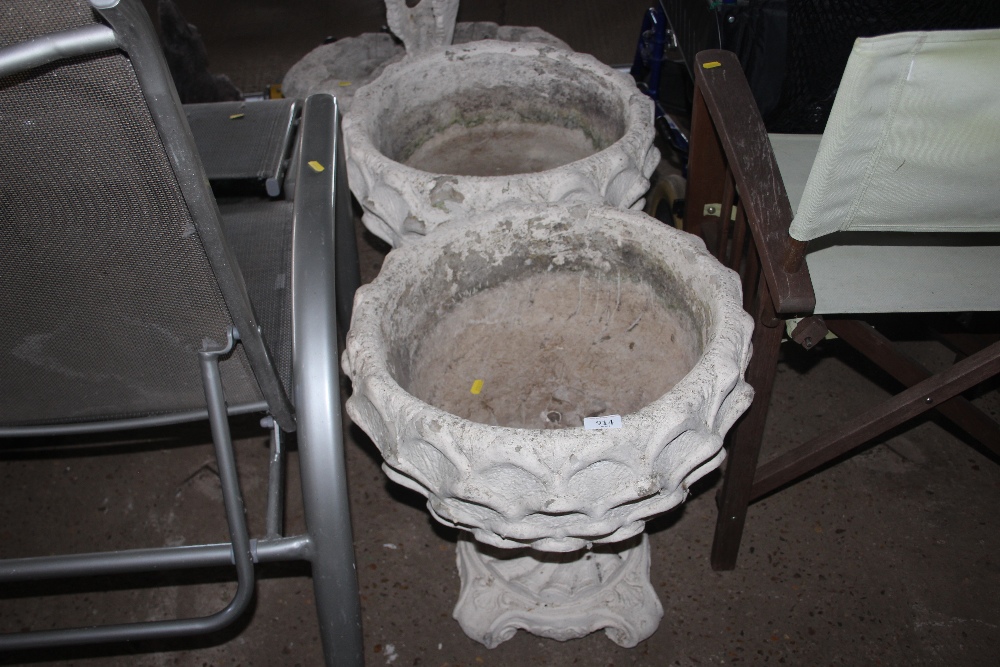 A pair of concrete planters raised on plinths