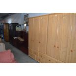 A pine effect triple wardrobe fitted five drawers