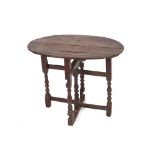 An antique oak small gate leg occasional table, the oval top raised on turned baluster columns